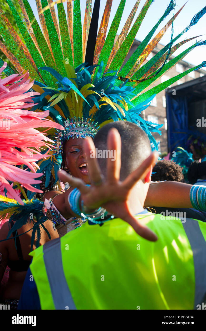 A black dancer dressed in colorful feather outfit and a skimpy bikini dance with a security guard along the route. Stock Photo