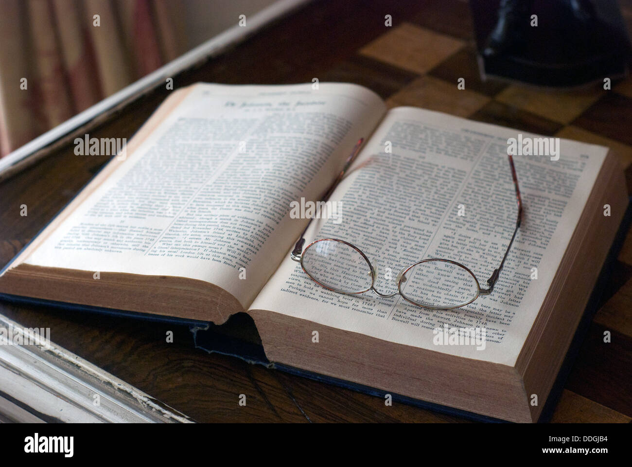 An old vintage book and spectacles glasses on a chess table in a british country house Stock Photo
