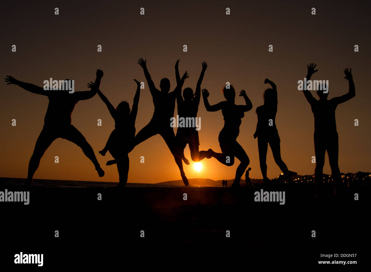 group of happy young people silhouettes jumping on the beach on ...