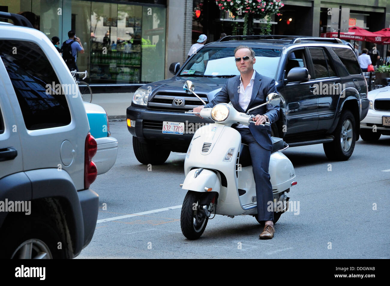 Businessman riding Vespa scooter in traffic in Chicago, Illinois, USA