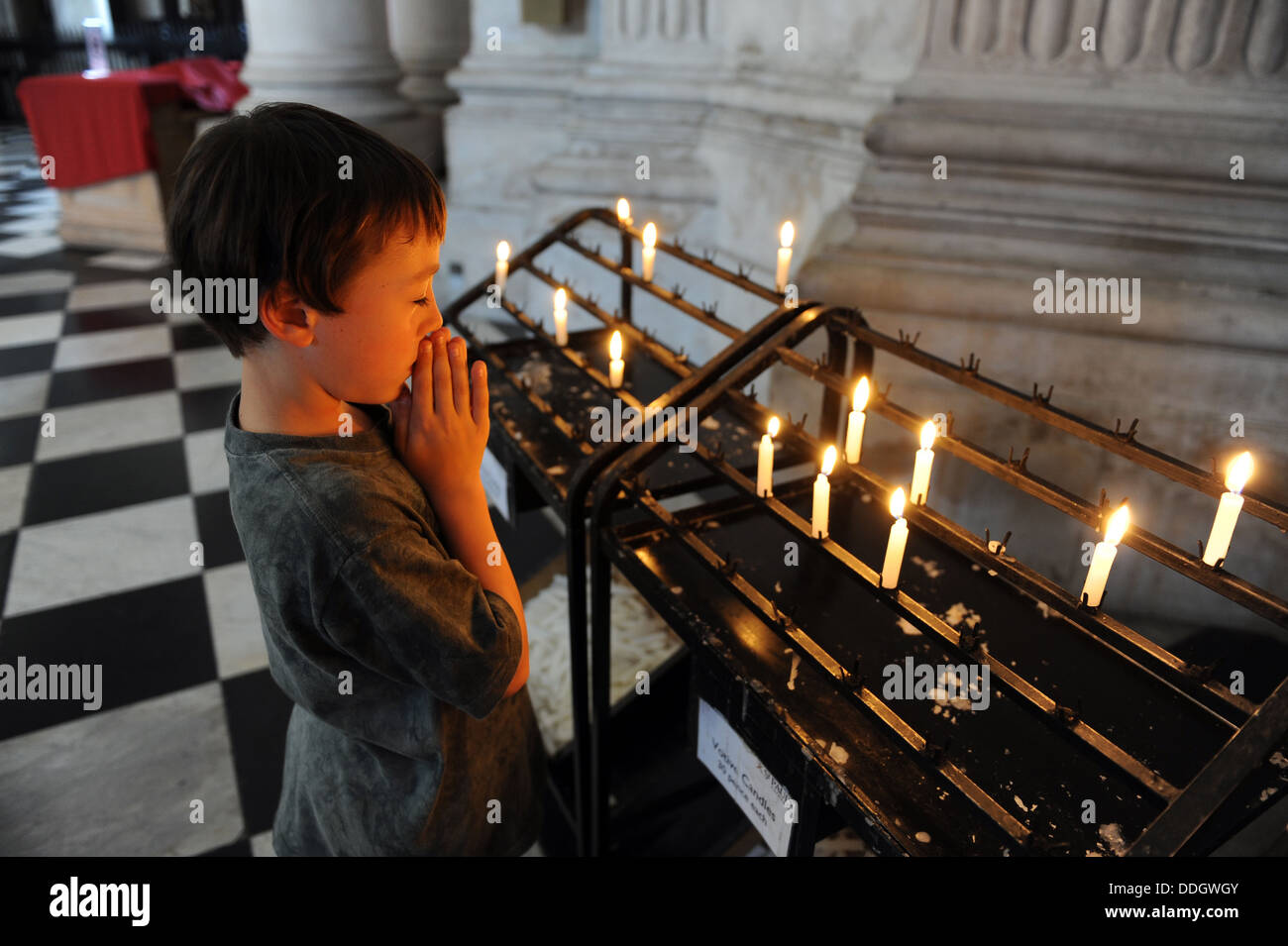 Young boy saying lighting a candle and saying a prayer in St Pauls Cathedral, London, uk Stock Photo