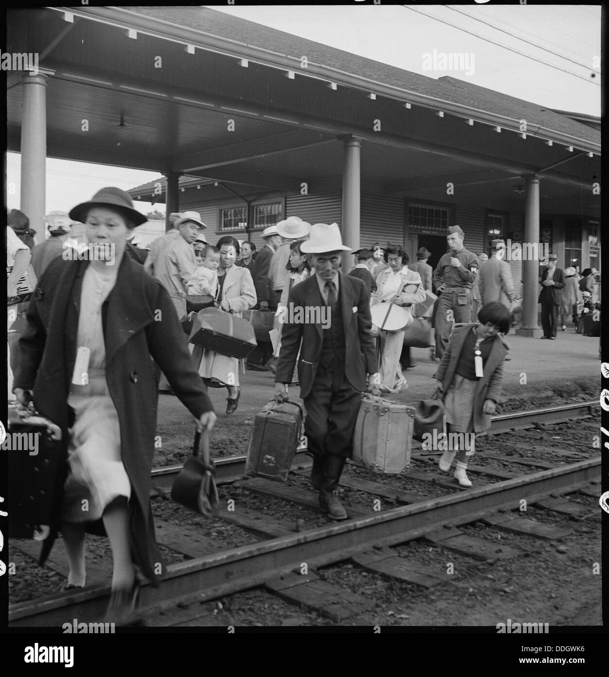In Woodland, California, families of Japanese ancestry are seen leaving the station platform to board a train. This photo likely captures a moment during World War II when Japanese Americans were relocated to internment camps under government orders. Stock Photo