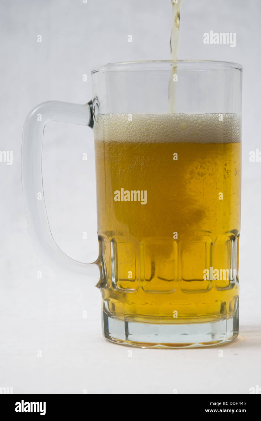 Cold mug of beer being poured with suds Stock Photo