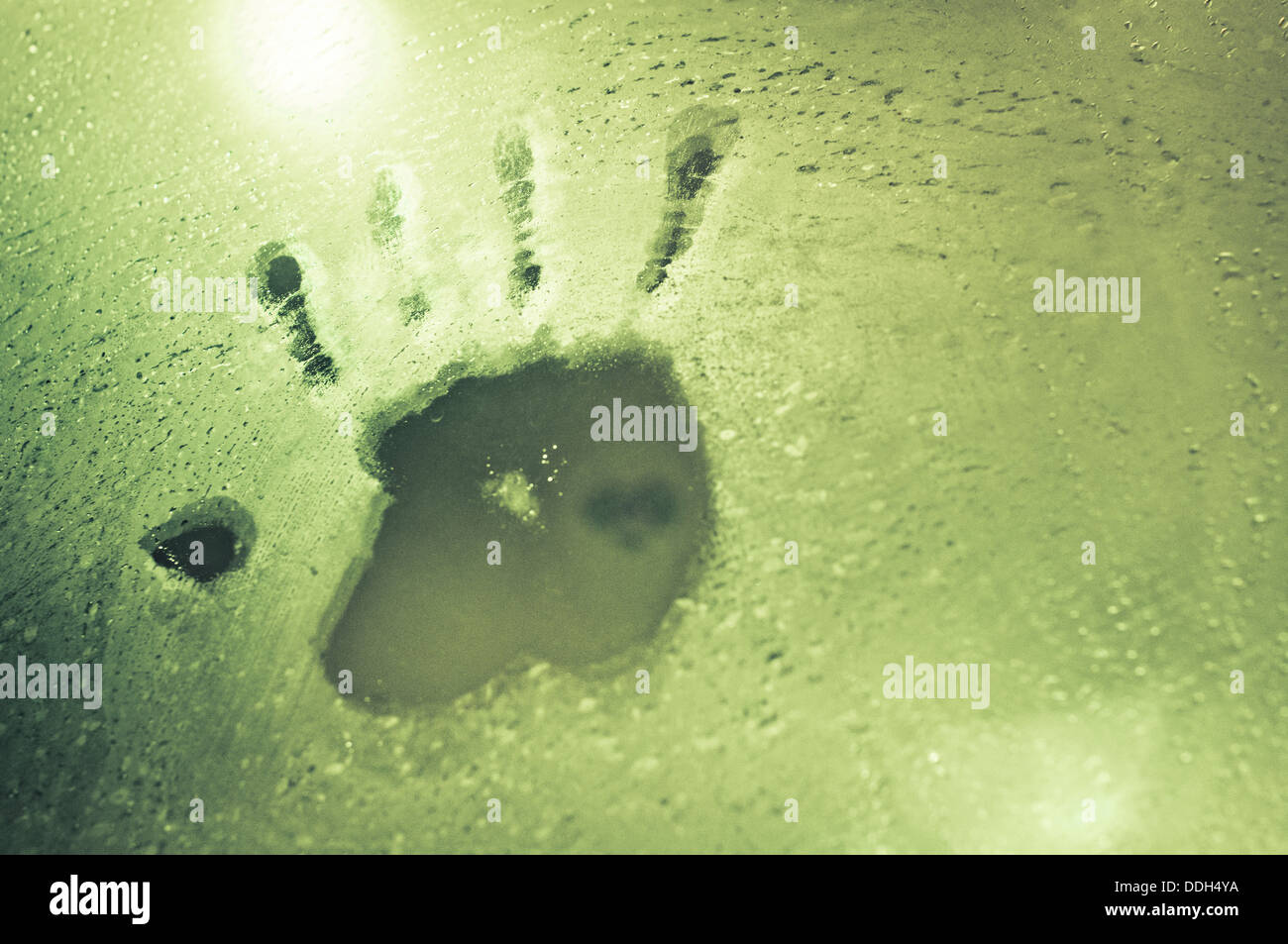 a hand print appears on a glass with water dews. Stock Photo