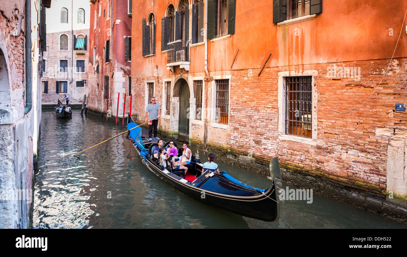 Gondolas with tourists sailing on a water street in Venice Italy Stock Photo