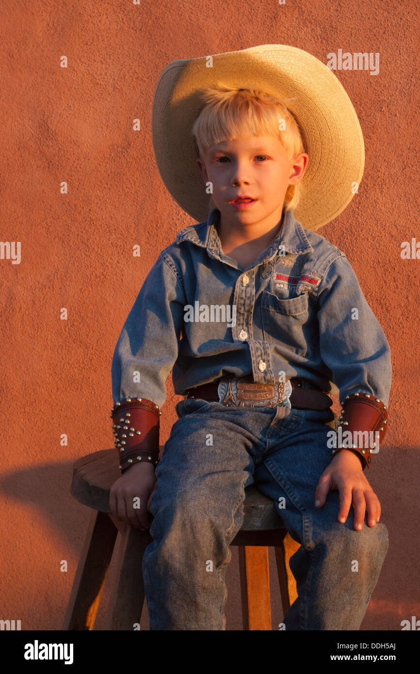 Four year old boy wearing cowboy hat, denim jeans and western shirt