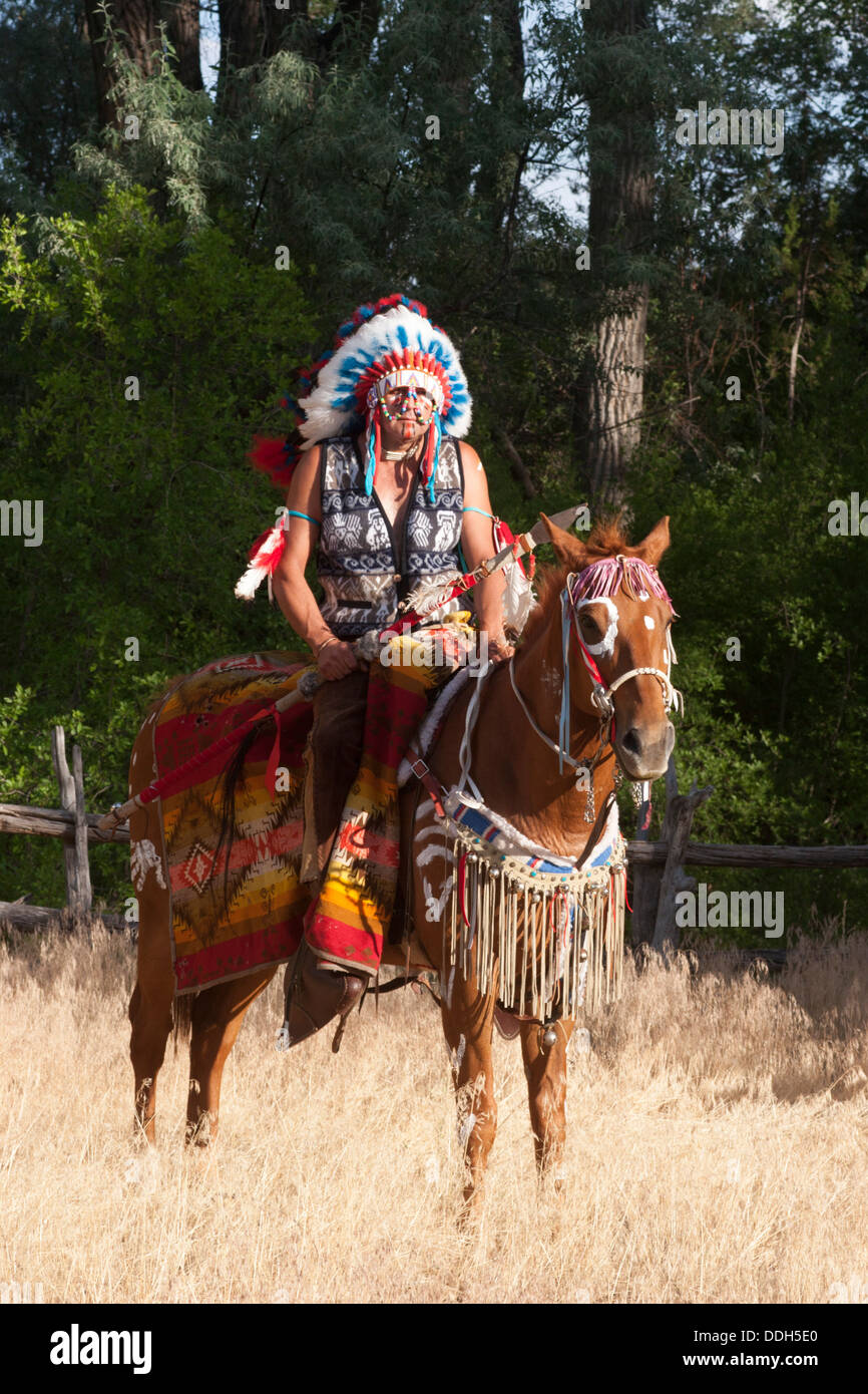 Warrior in Comanche clothing riding chestnut horse Stock Photo