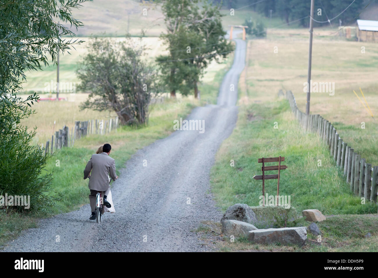 Bride and groom riding a tandem bicycle on their wedding day in Oregon's Wallowa Valley. Stock Photo