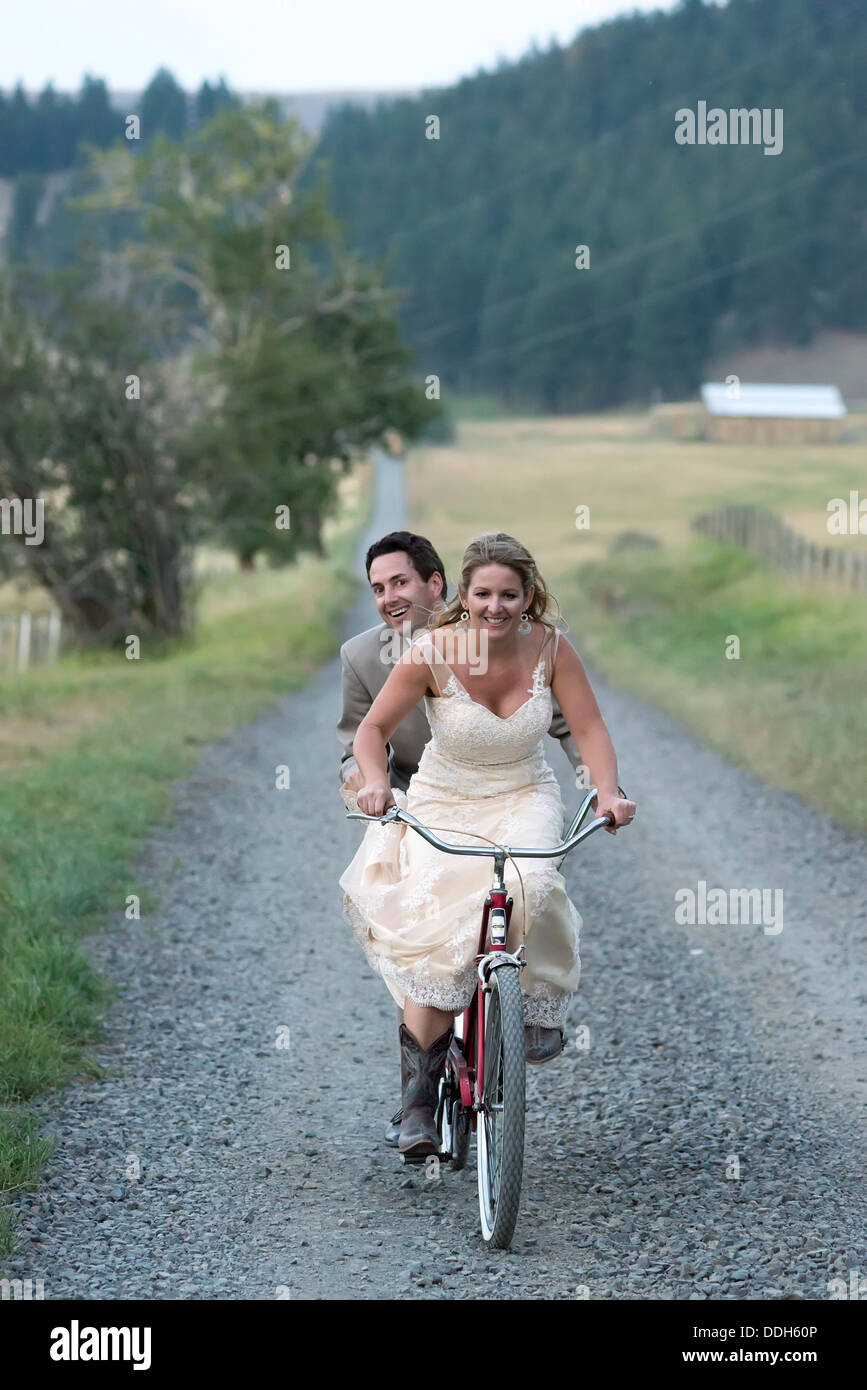 Bride and groom riding a tandem bicycle on their wedding day in Oregon