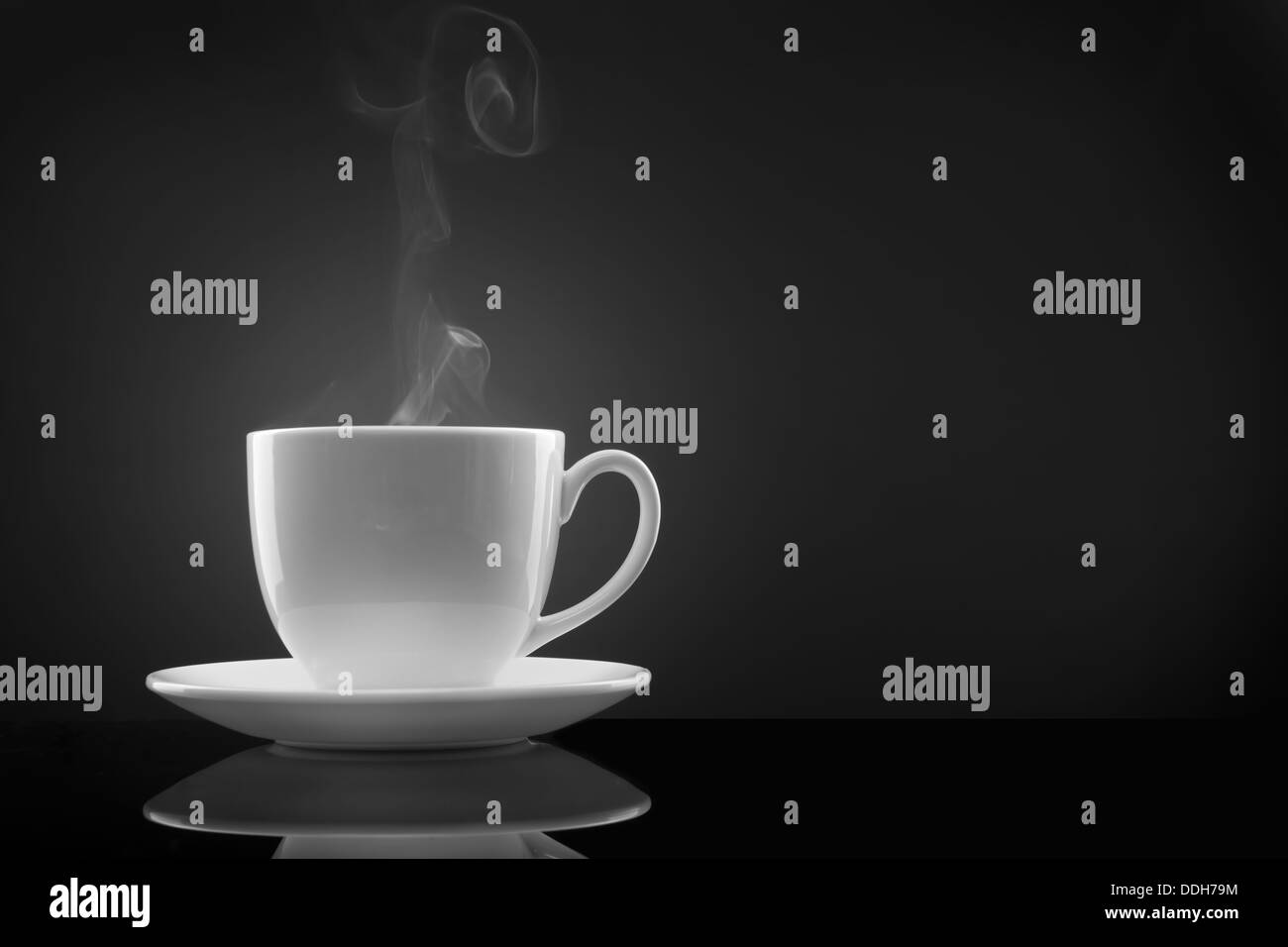 white cup with hot liquid and steam on black Stock Photo