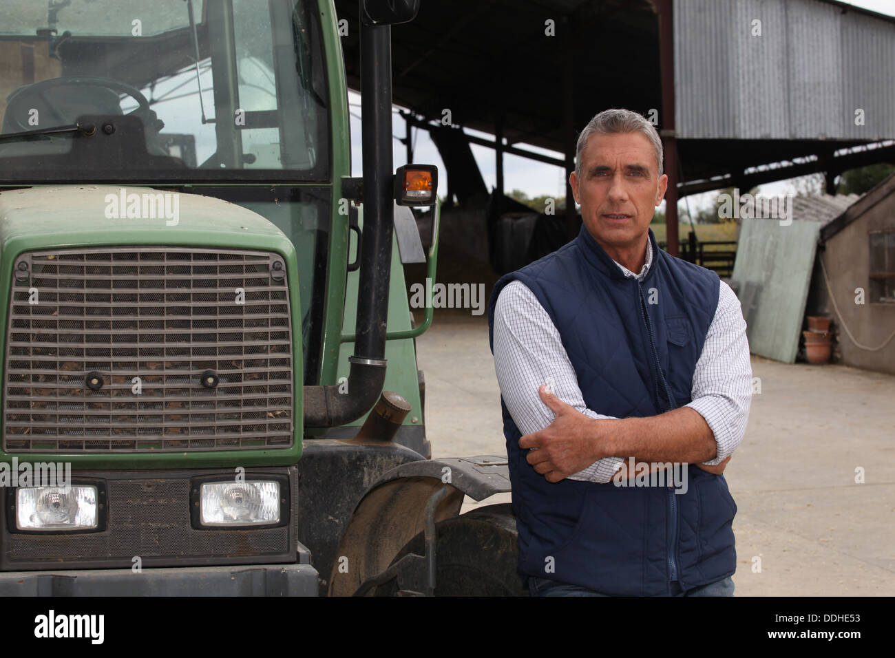 Farmer standing beside a tractor Stock Photo - Alamy