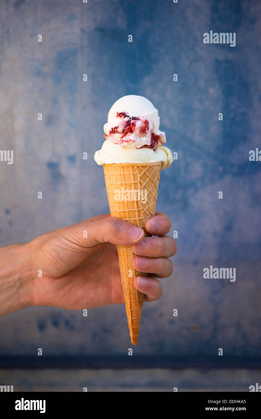 Man holding cherry ice cream in wafer cone Stock Photo