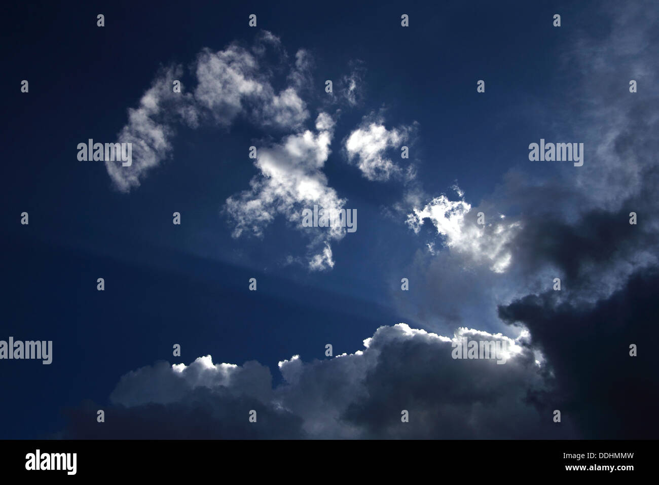 Light rays shining through wispy clouds, atmospheric clouds Stock Photo