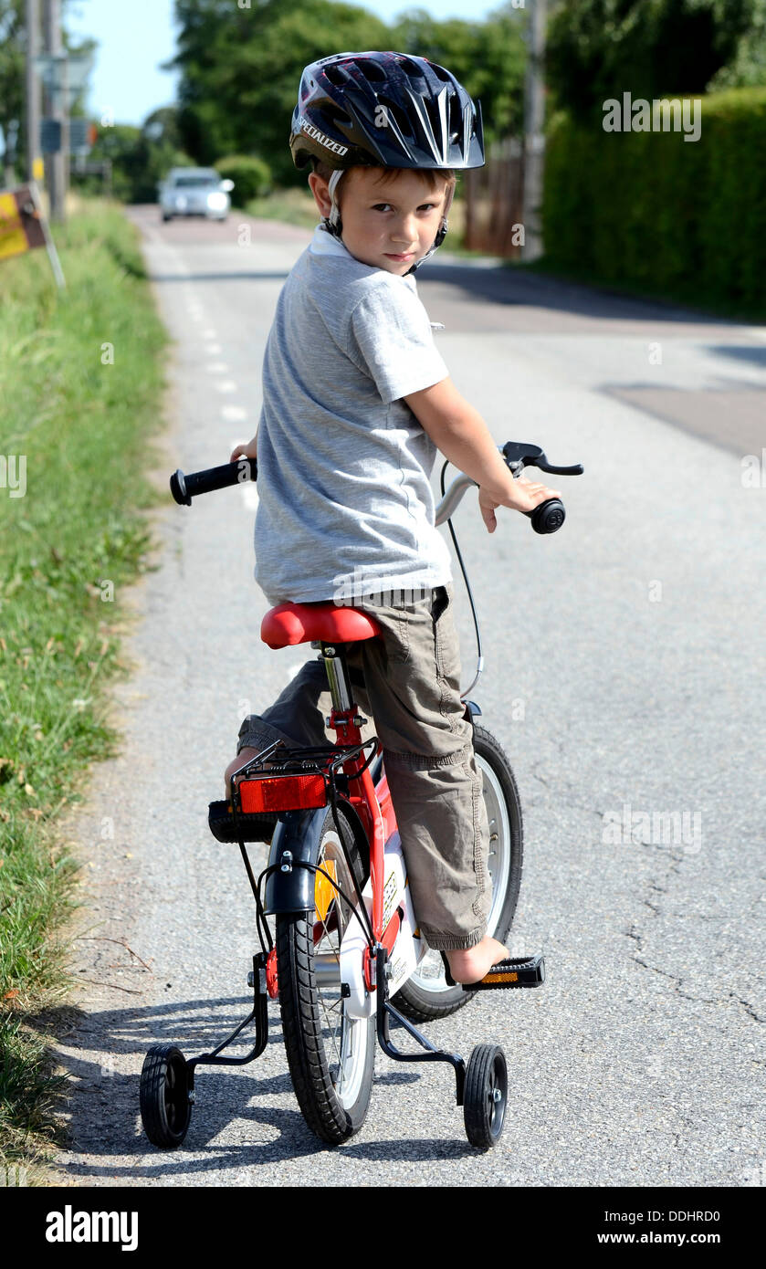 Boy riding a bicycle with training wheels Stock Photo - Alamy