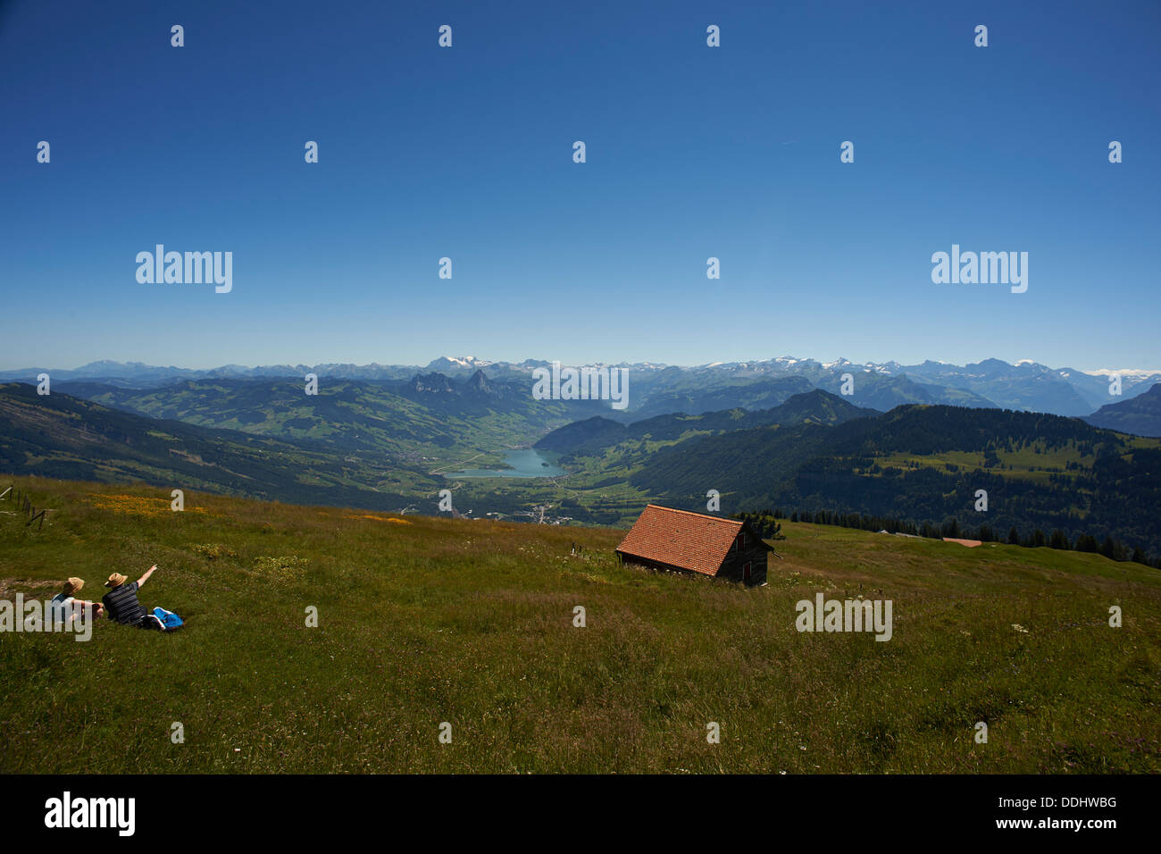 Mountain meadow with hikers, distant view towards the Alps Stock Photo