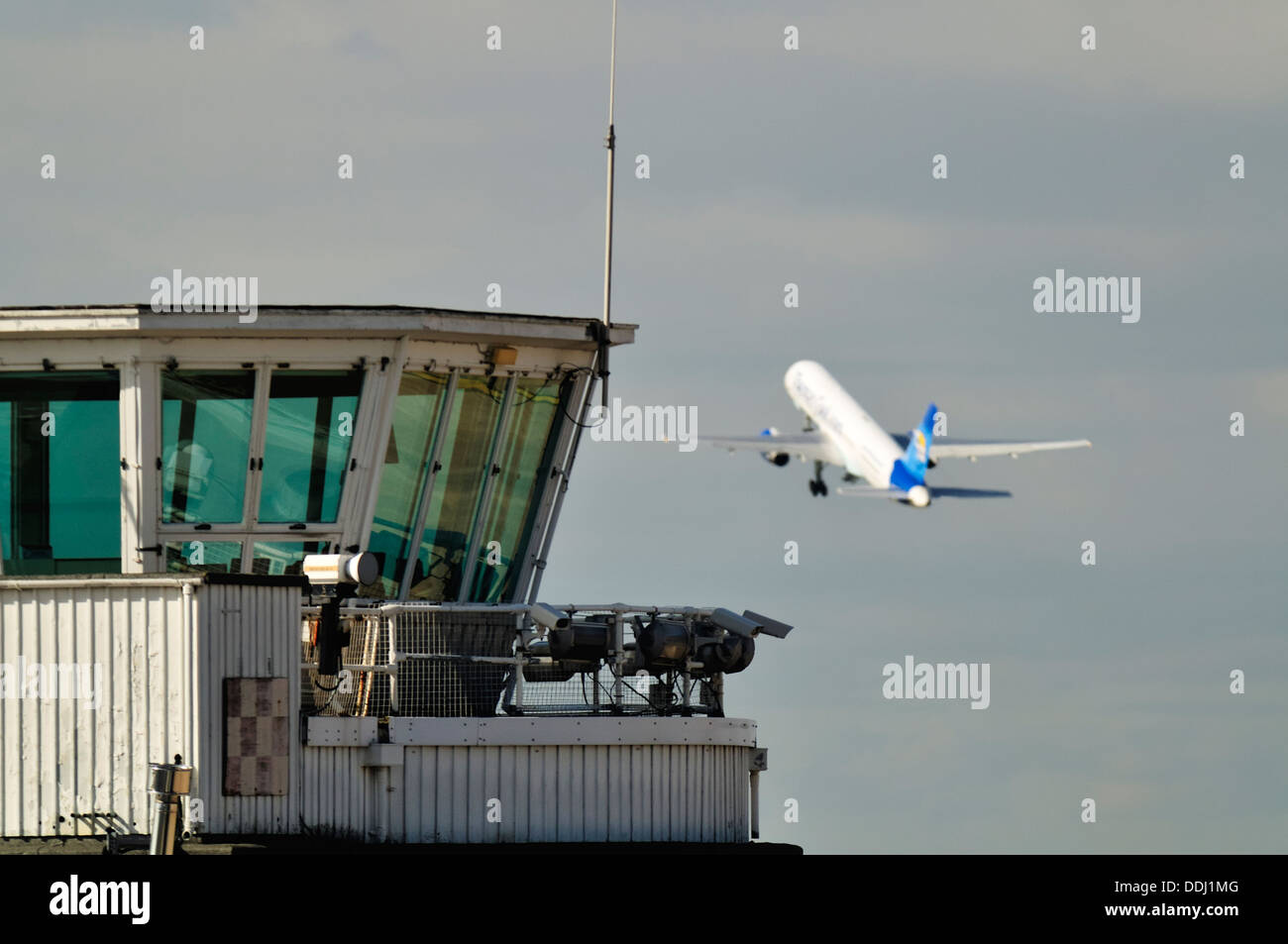The old Elmdon air traffic control tower with a Thomas Cook Boeing 757 taking off in the background Stock Photo