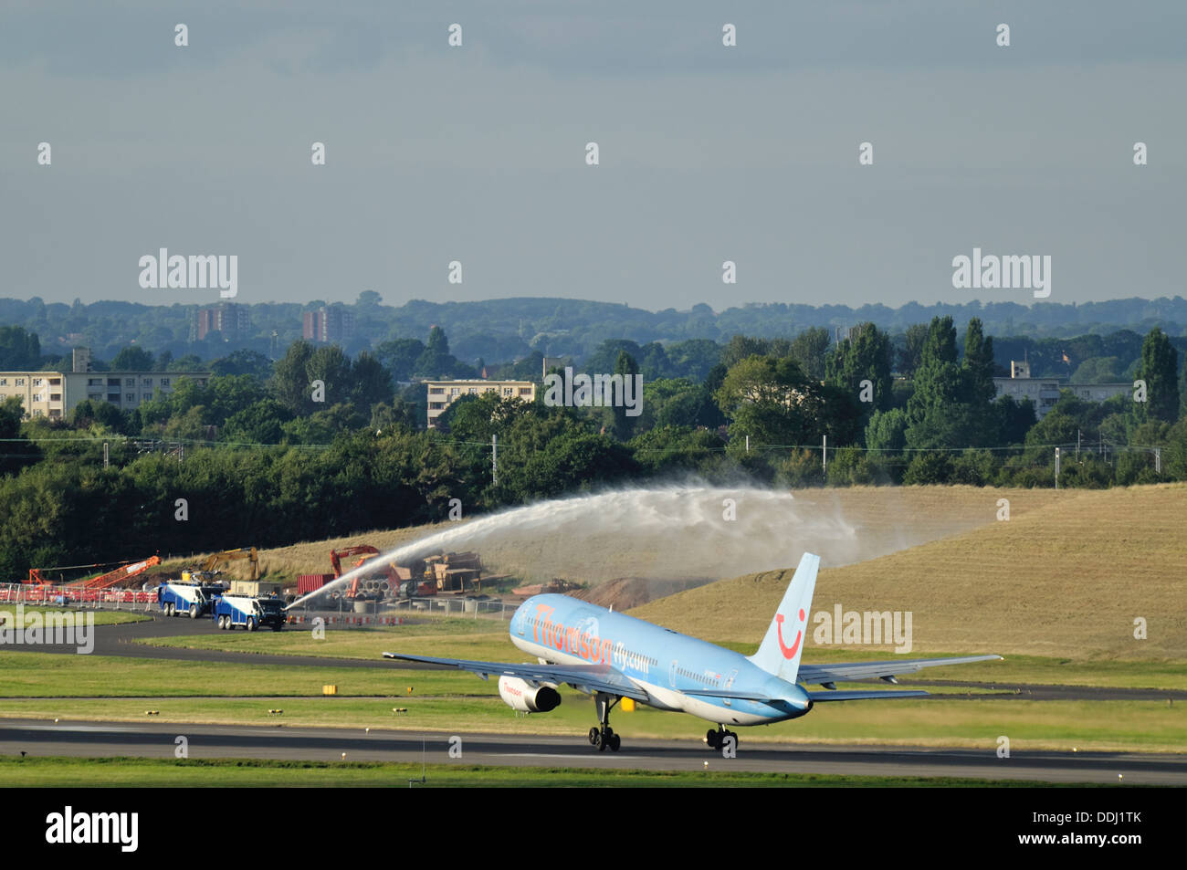 A Thomson Boeing 757 aircraft takes off whilst an airport fire engine sprays water in the background. Stock Photo