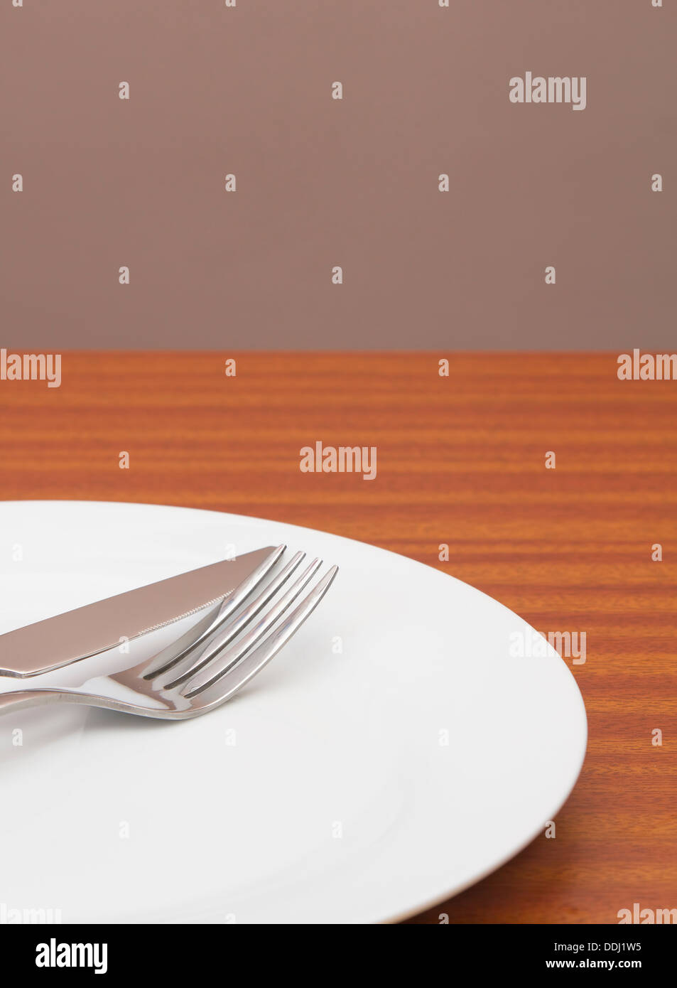 White place setting on table with wall behind Stock Photo