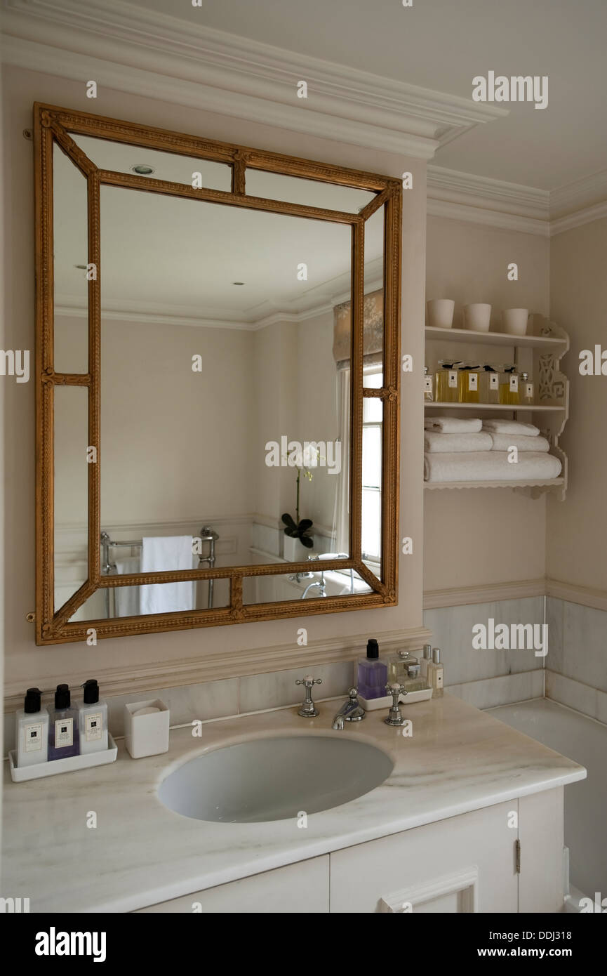 A beveled frame mirror from Beaumont and Fletcher above a white marble vanity unit Stock Photo