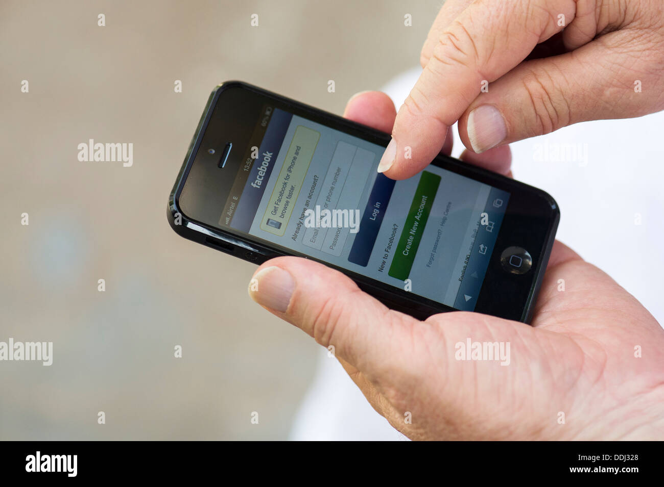 Senior man using Apple iphone 5 to sign into facebook Stock Photo