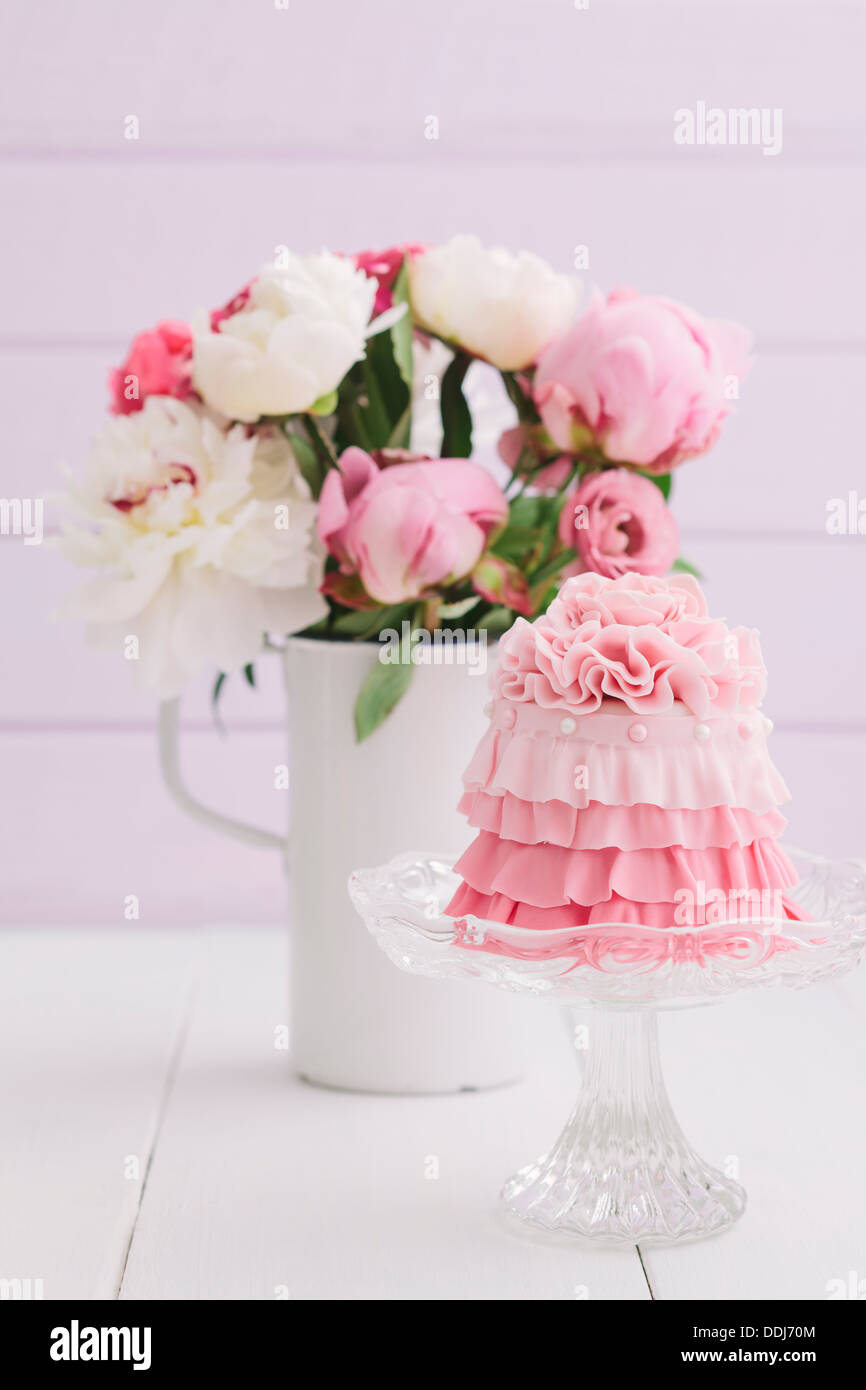 Pink mini cake with flower bouquet on table, close up Stock Photo