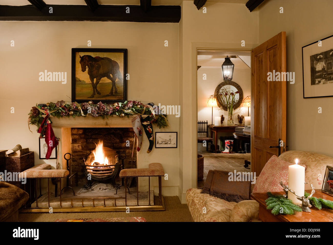 Fireplace with club fender in cosy living room with Howard style armchair and view through to hall Stock Photo