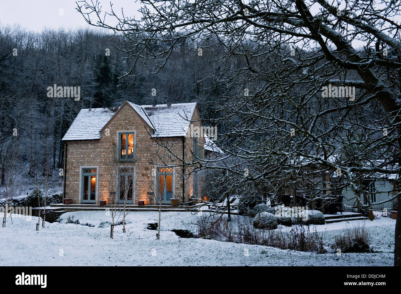 Wintry exterior facade of Keepers Cottage seen from the garden and over the stream Stock Photo