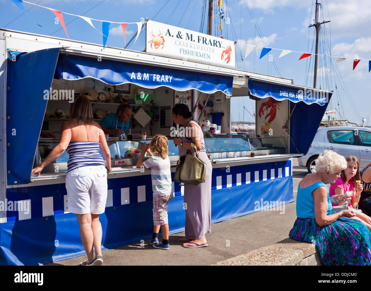 Customers buying at the Seafood stall on the quayside at Wells next
