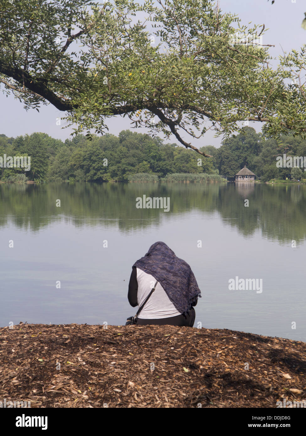 Muslim woman sitting along the lake in Prospect Park, Brooklyn, NY. Stock Photo