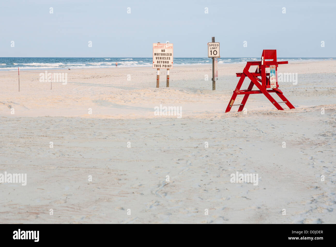 Unmanned red lifeguard station next to sign warning of no motorized traffic on Daytona Beach, Florida Stock Photo