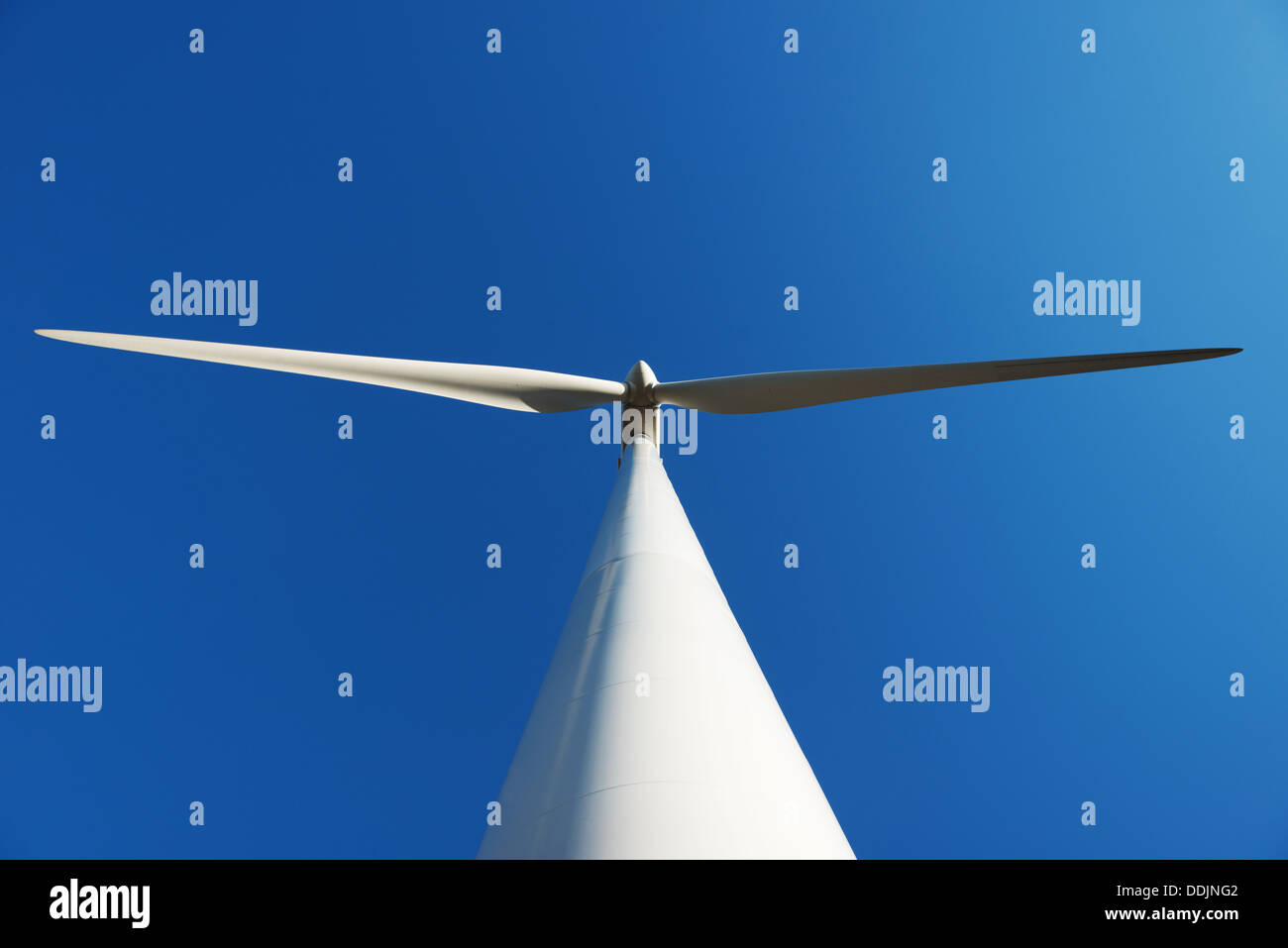 A wind turbine taken from below against blue sky Stock Photo