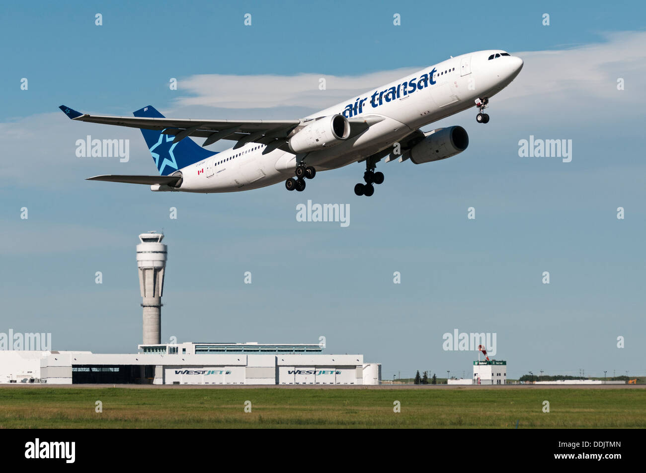An Air Transat Airbus A330 wide body jetliner takes off from Calgary International Airport, airport buildings in the background. Stock Photo