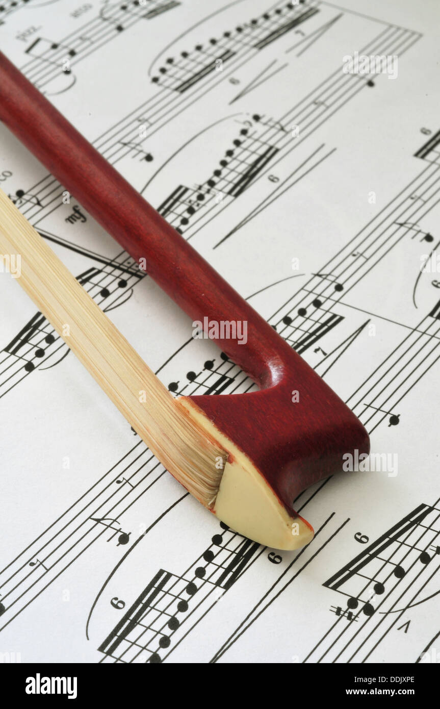 Violin bow tip on sheet music background Stock Photo