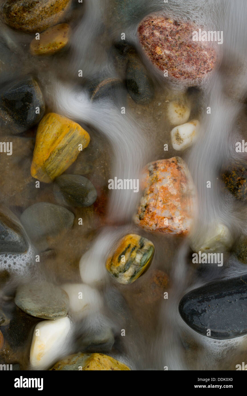 Mixed pebbles on the beach with the surf receeding. Borth, Ceredigion, Wales. March. Stock Photo