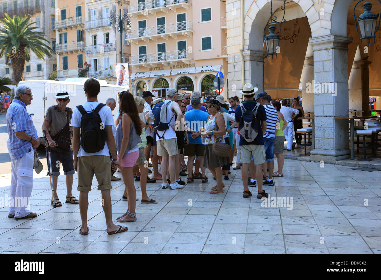 Tourists on a guided tour at the Liston, an arched colonnade lined with cafes, on the edge of the Spianada, Corfu Town in Greece Stock Photo