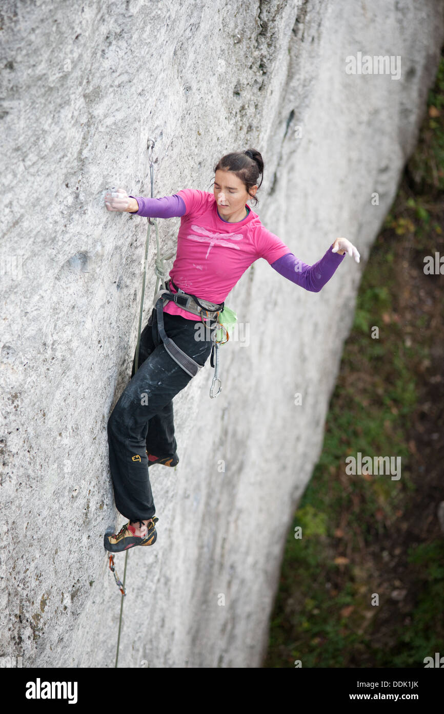 Elevated view of female sport climber leading vertical limestone rock wall. Jura Krakowsko Czestochowska. Poland. Europe. Stock Photo