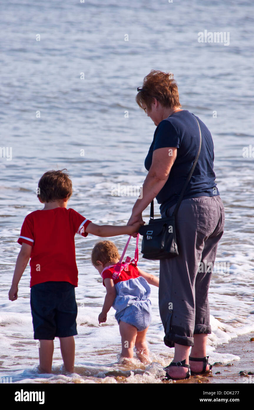 Grand mother and children paddling in the sea Stock Photo