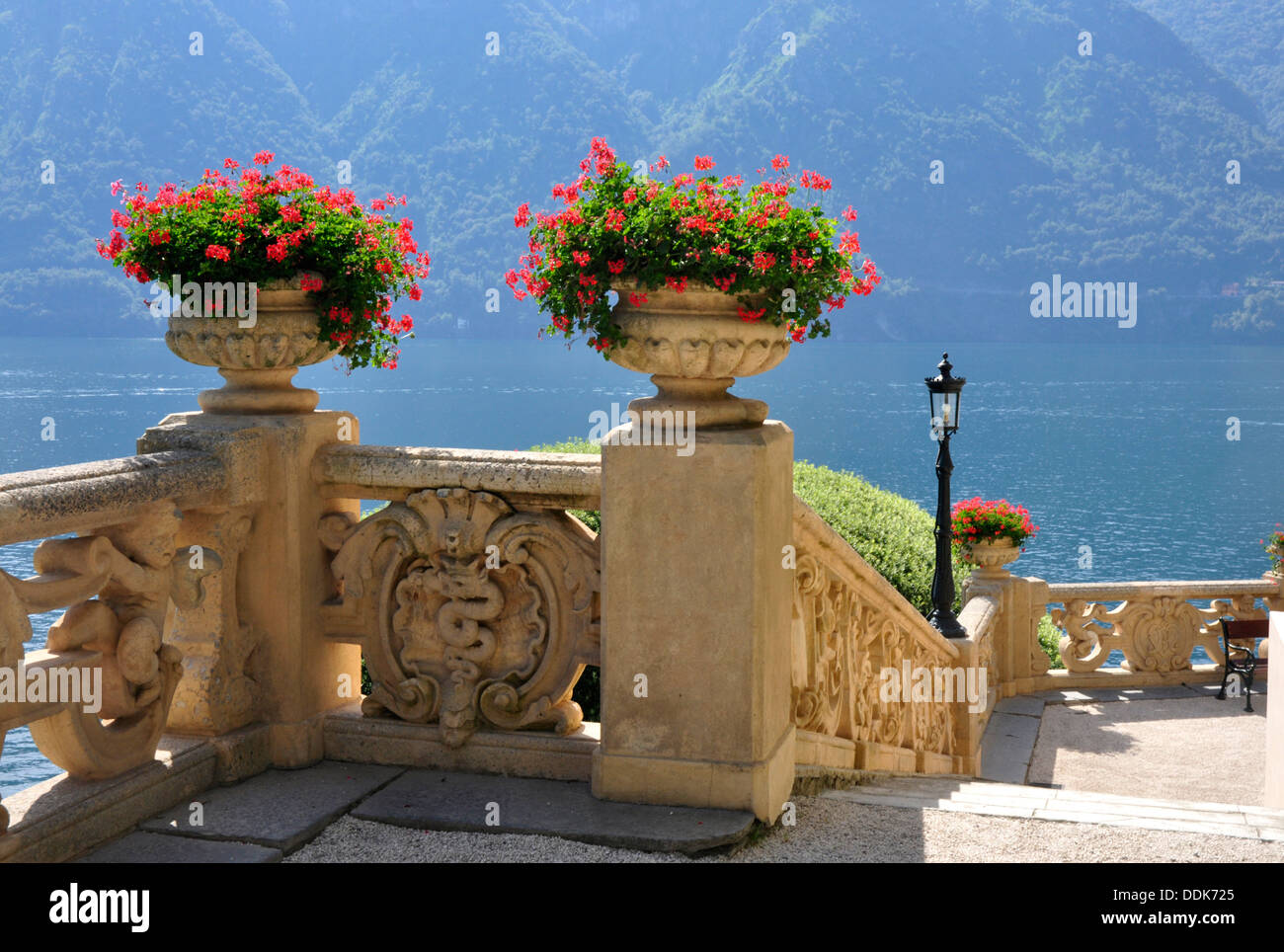 Italy - Lake Como - Lenno - Villa Balbianello - terrrace - decorative  carved balustrade - ornamental  flowers  - lake backdrop Stock Photo