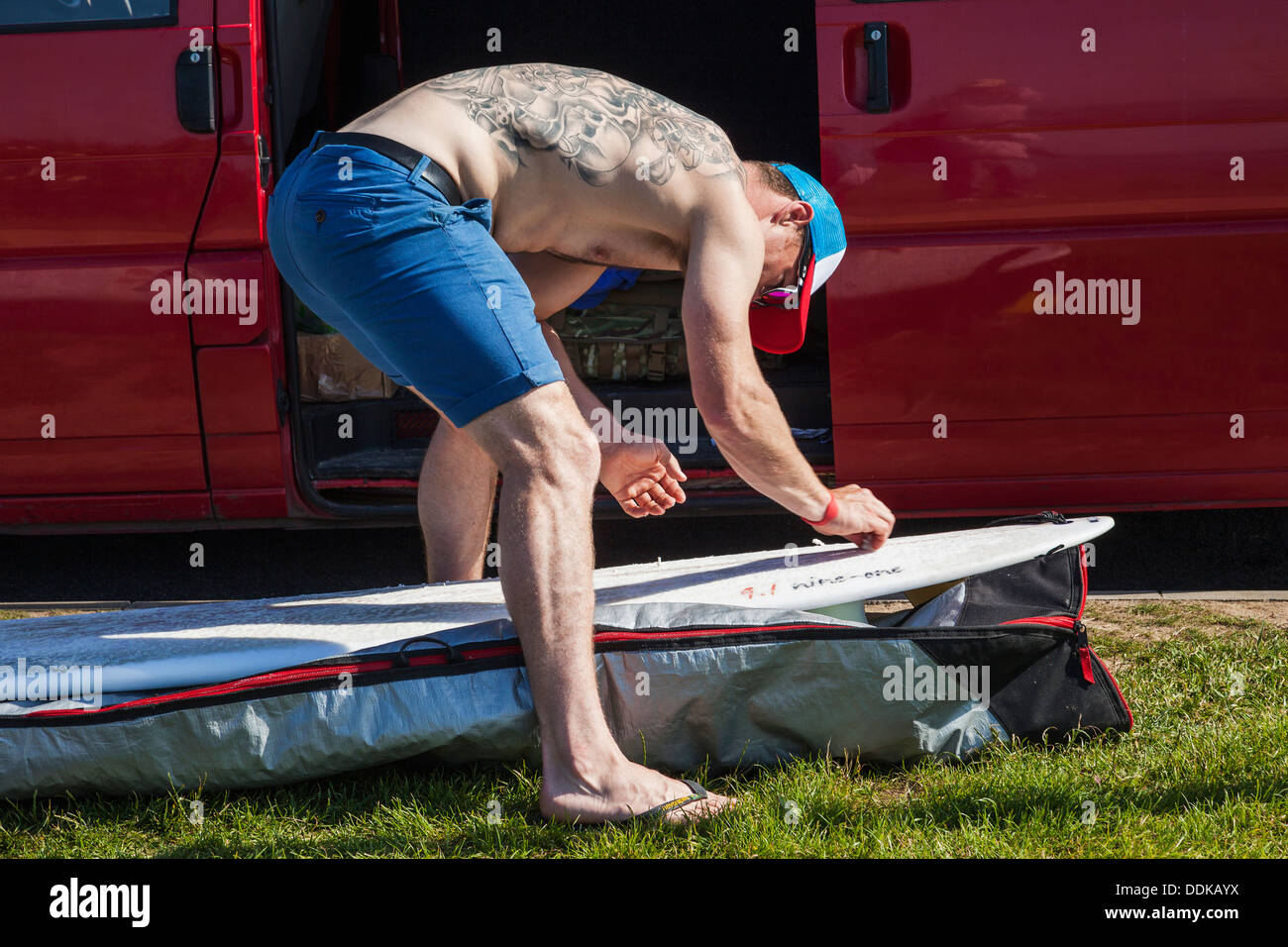 England, Cornwall, Newquay, Fistral Beach, Surfer applying wax to a Surfboard Stock Photo