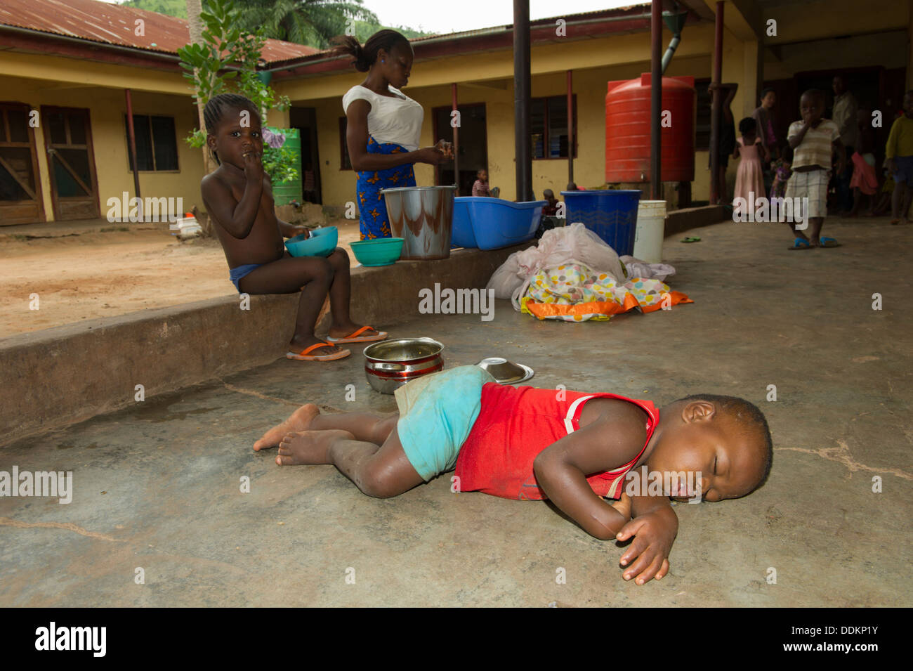 Toddler sleeping on concrete floor in a dormitory hall in Nigeria Stock Photo