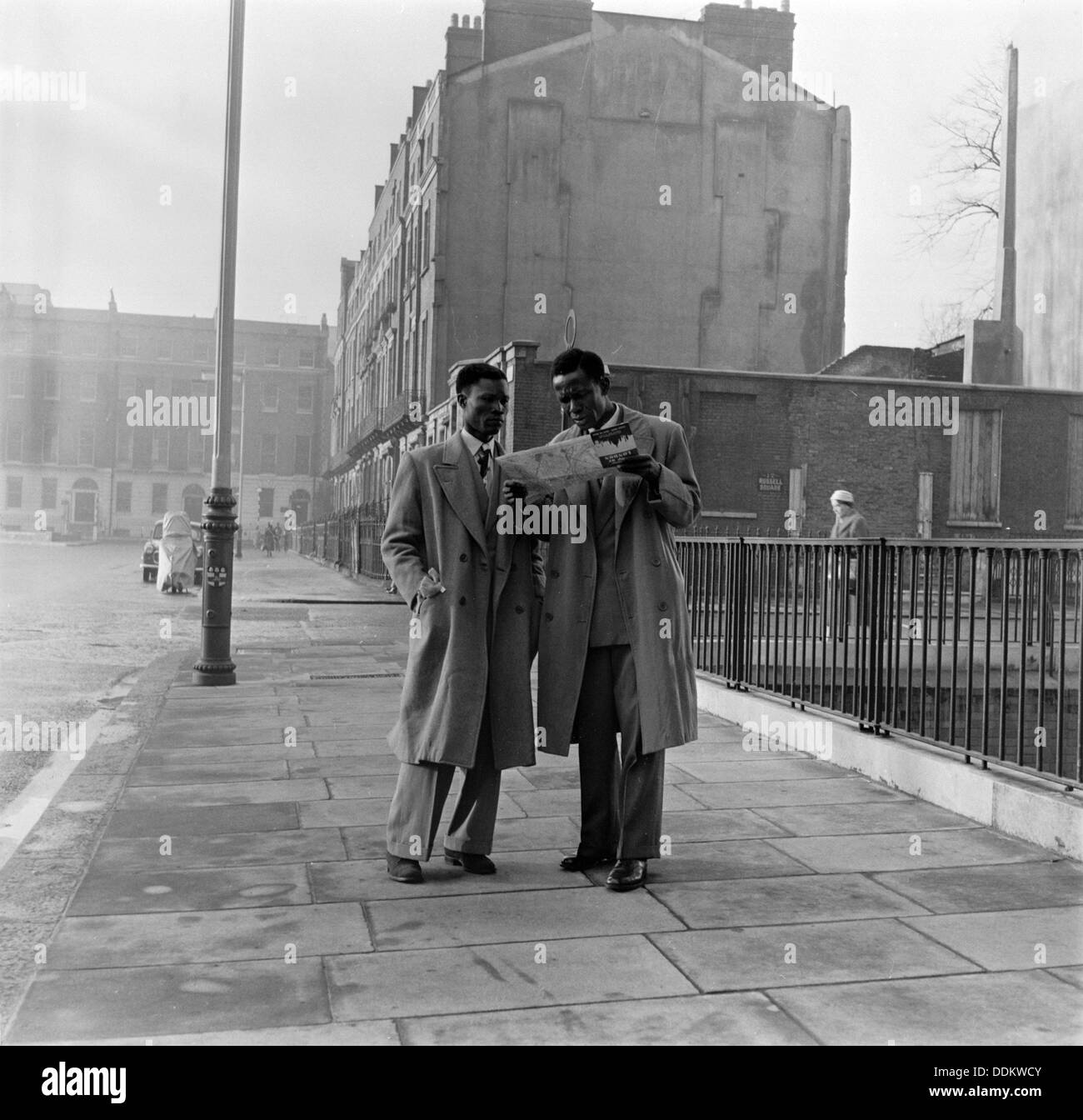 Two Afro-Caribbean men reading a map in the street, London, (c1950s?).   Creator: Henry Grant. Stock Photo