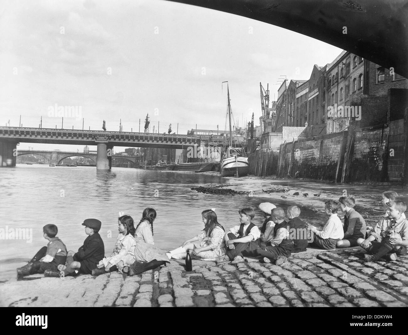 Children on the cobbled causeway under Southwark Bridge, London, c1930. Artist: George Davison Reid Stock Photo