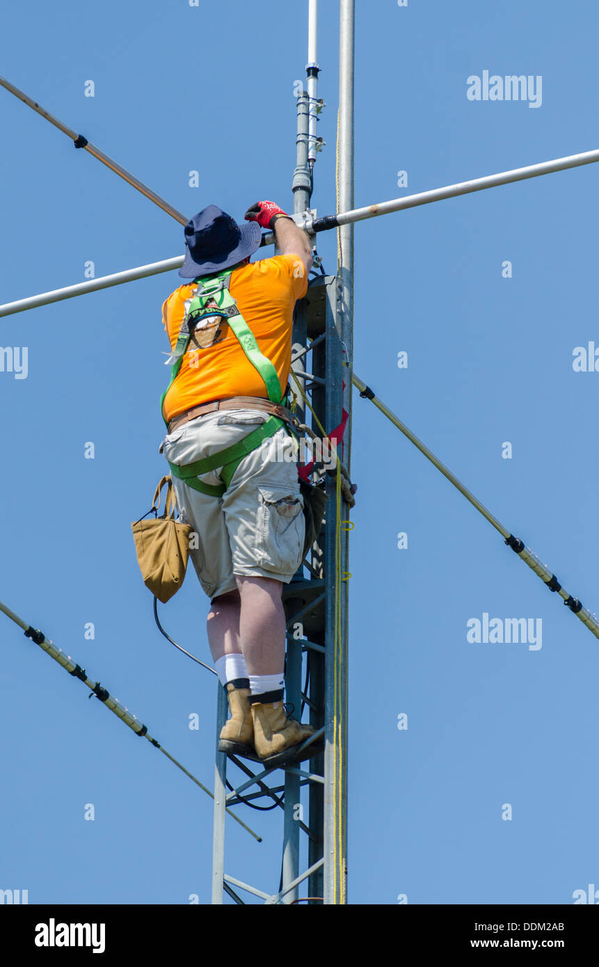 Man installing a amateur radio antenna at the top of radio tower. Stock Photo