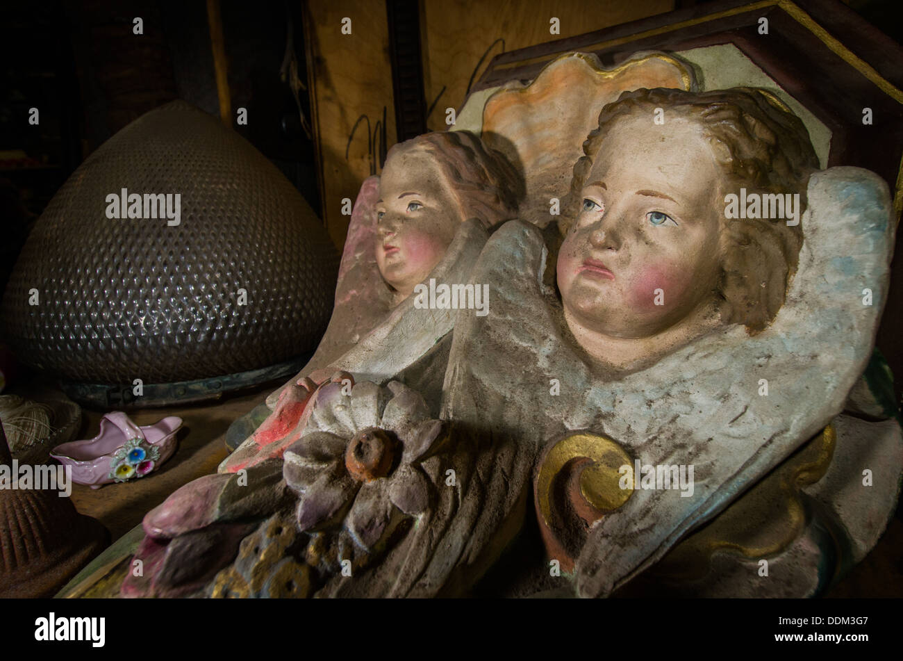 Dirty and sooty cherub statuary lies on a shelf amongst other bric-a-brac. Stock Photo
