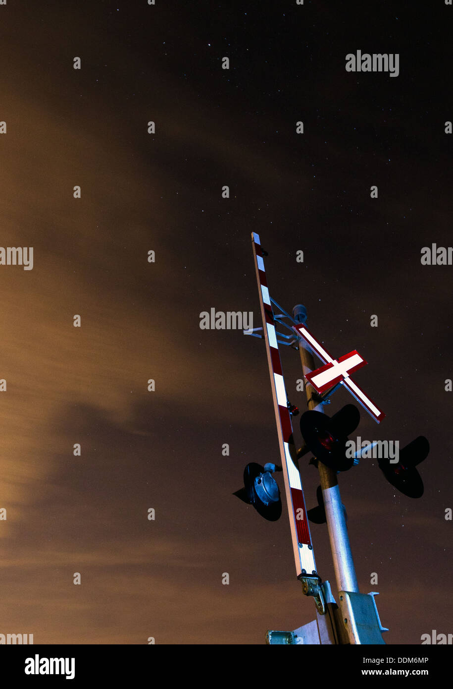 A railroad crossing arm at night. Stock Photo