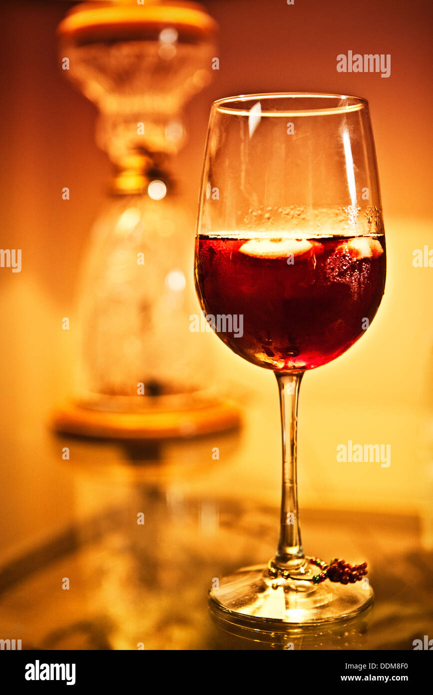 glass of red wine on a glass tabletop next to a lamp base Stock Photo