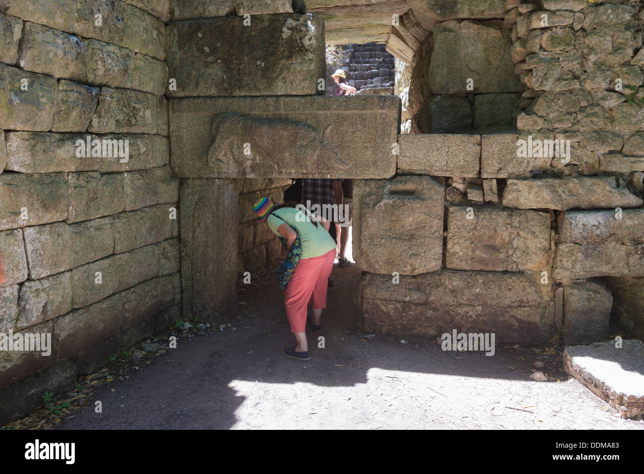A tourist ducks under the Lion carving of the Lion Gate in the 4th century wall at Butrint, Albania Stock Photo