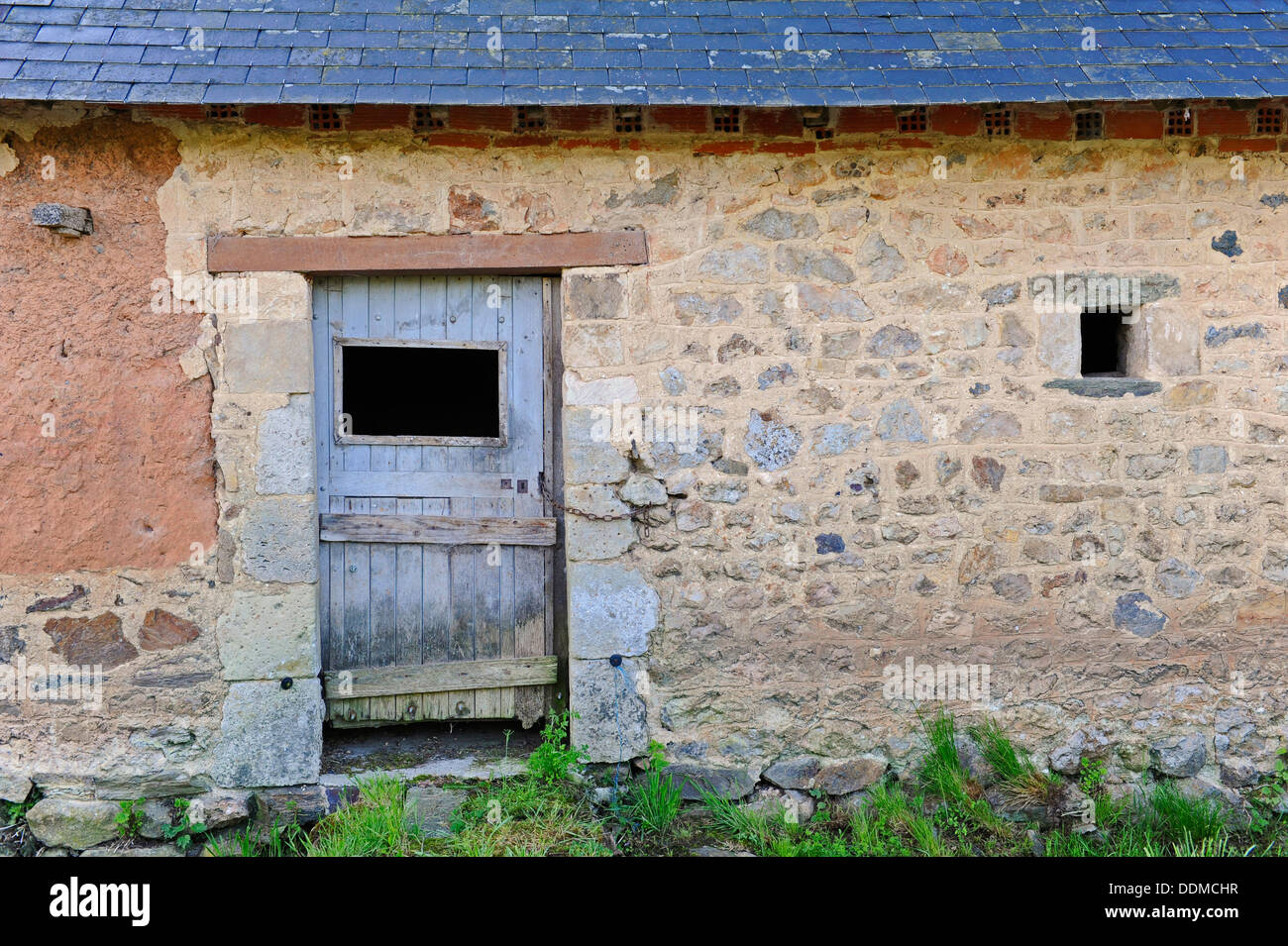 Traditional French farm buildings made from a mixture of red mud, stone with wood timbered frames for windows and doors. Stock Photo