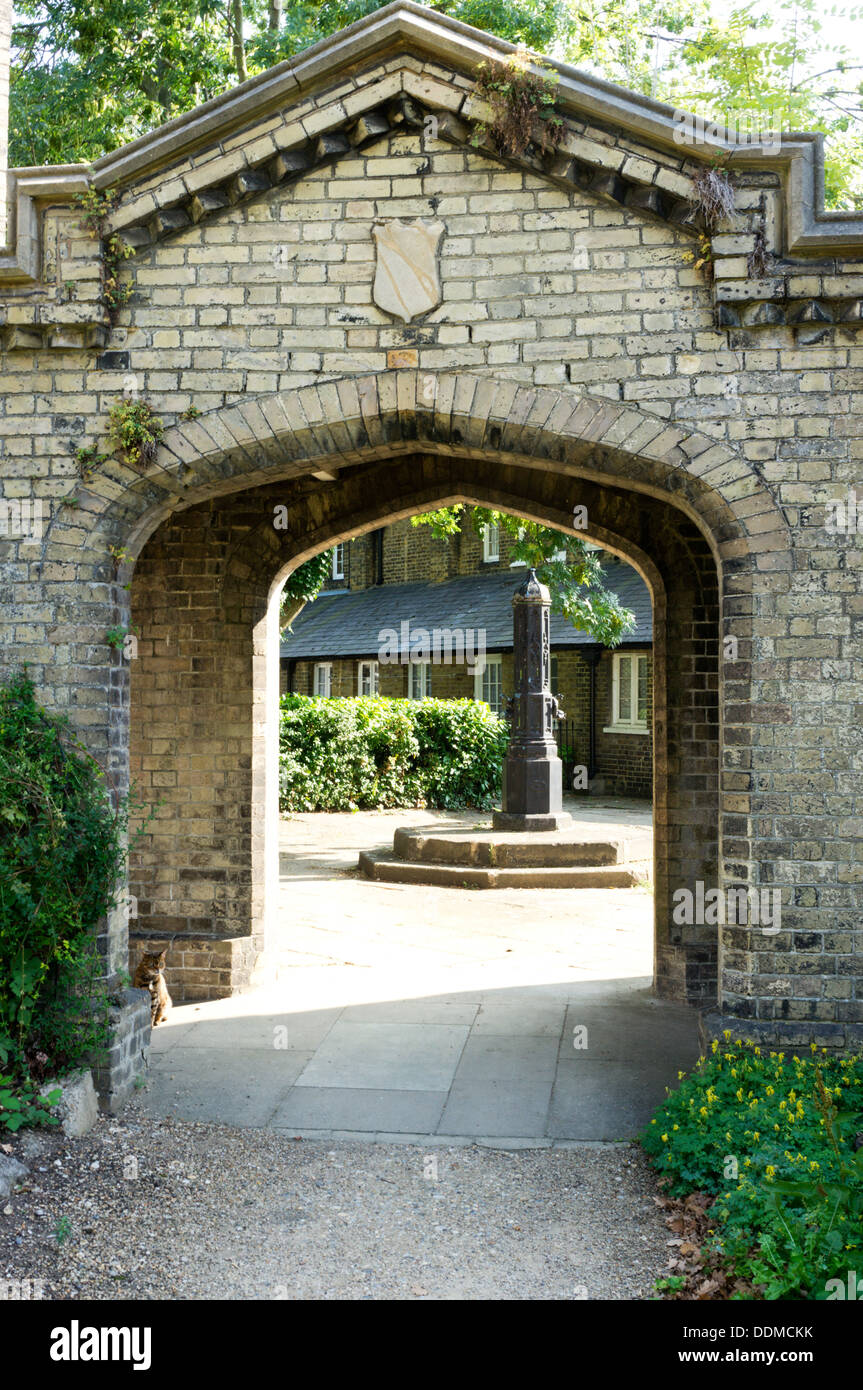 A pump in a residential square seen through a brick archway at the 'Royal Watermen's Almshouses in Penge, south London. Stock Photo