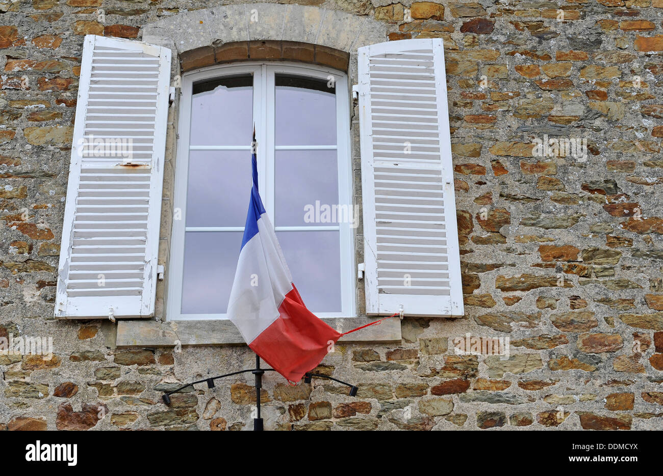 Open shuttered windows at the French mayors office with French flag at Le Hommet dArthenay, Normandy, France Stock Photo